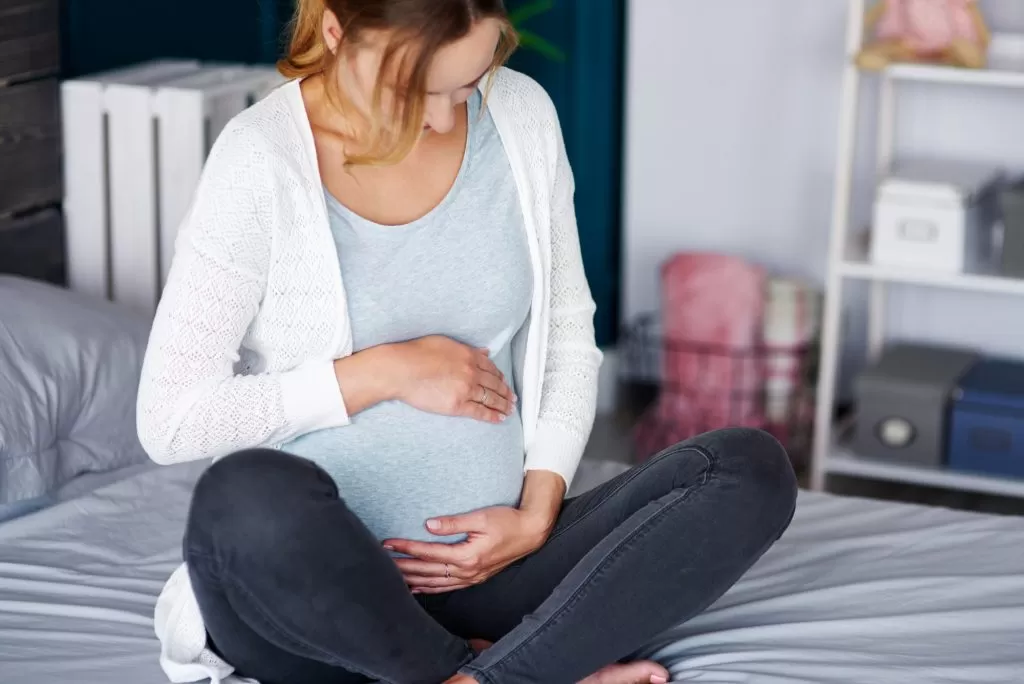 affectionate pregnant woman touching her belly home